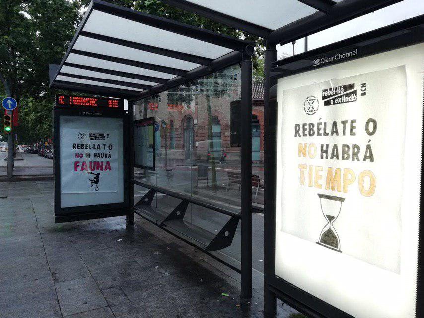 Cartells: "Rebel·la't o no hi haurà fauna", "Rebelate o no habrà tiempo" a una parada d'autobús