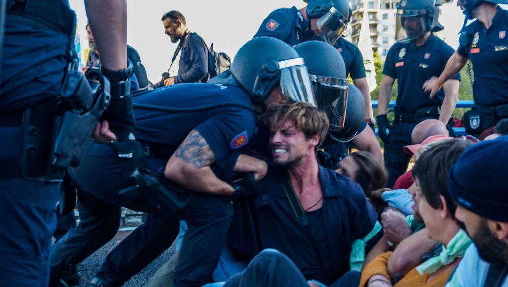 Picture of a rebel peacefully resisting against the violent action of a policeman